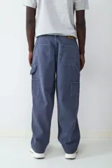 Pantalón estilo carpintero de corte holgado, color azul marino con efecto lavado. Presenta bolsillos laterales funcionales, cierre frontal con botón y costuras reforzadas.