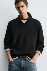 Polo de punto de manga larga con cuello solapa y cierre frontal de botones. Presenta un diseño de corte regular con aberturas laterales en el bajo.