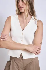 Chaleco de punto color crema con escote en V y cierre frontal con botones a tono.