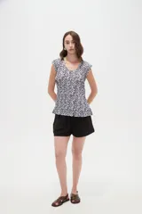 Blusa de poliéster sin mangas con cuello redondo y estampado geométrico en tonos marrones y blancos, de corte holgado y diseño fluido.