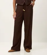 Pantalón de corte recto confeccionado en mezcla de viscosa y lino. Presenta cintura elástica con cordón ajustable y bolsillos laterales.
