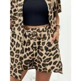 Conjunto de dos piezas compuesto por una camisa de manga corta con cuello italiano y cierre frontal de botones, y un short con cintura elástica y bolsillos laterales. Ambas prendas presentan un diseño estampado de animal print.
