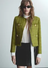 Chaqueta de tweed en color verde lima, con diseño recto, cuello redondo y manga larga. Presenta botones efecto joya y cuatro bolsillos frontales.