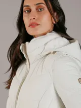 Campera acolchada de Calvin Klein en color blanco, confeccionada en una mezcla de poliéster y elastano que ofrece elasticidad y confort. Presenta un diseño con cuello alto, capucha, cierre frontal de cremallera metálica y bolsillos laterales con cierre. Su acabado tiene un ligero brillo y cuenta con un calce entallado gracias a sus costuras horizontales.