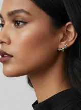Par de aros tipo ear climber plateados con diseño de tres flores pequeñas, cada una con un cristal engarzado en colores rosa, verde y azul.