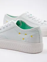 Zapatillas bajas de lona color celeste con plataforma blanca texturada y detalle de flores bordadas en el lateral.