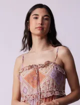 Vestido midi de gasa estampada con motivos geométricos en tonos naranja, lila y beige. Tiene breteles finos regulables, escote en V con volados y falda asimétrica con volados.