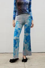 Pantalón de calce ajustado con diseño acampanado en el ruedo, confeccionado en tela sublimada con estampado artístico de bosque en tonos azules y celestes.