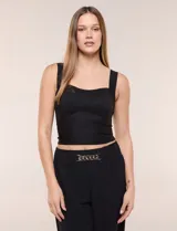 Top crop musculosa de Allie Rose, de calce ajustado y estructurado, color negro, confeccionado en tejido de punto elastizado con textura acanalada fina. Presenta escote corazón, pechera forrada en la zona del busto, breteles anchos y costuras de corte corsetero.