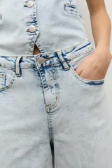 Jean wide leg de tiro medio con lavado claro, corte recto y holgado en las piernas, con diseño clásico de cinco bolsillos y cierre frontal con botón y cremallera.