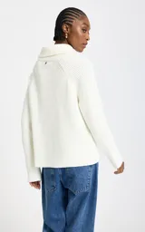 Sweater blanco de punto acanalado con cuello alto amplio y cierre de cremallera asimétrico, hombros caídos y mangas largas.