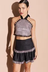 Top halter con acabado brillante, escote alto y detalles de ojalillos decorativos en los bordes. Diseño con espalda descubierta y cierre ajustable.