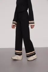 Pantalón negro de tejido de punto con corte palazzo y cintura alta. Presenta dos franjas horizontales color crema en el ruedo.