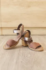 Sandalia de cuero marrón con tira frontal en cuero y correa al tobillo metalizada con hebilla ajustable. Cuenta con tacón ancho y bajo de acabado símil madera.