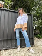 Camisa blanca de lino con mangas largas y corte holgado. Presenta un bloque de color marrón en la parte inferior.