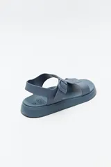 Sandalia baja negra con tiras anchas y hebilla lateral.