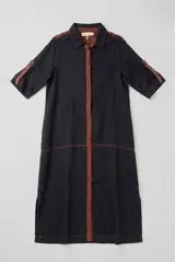 Vestido chemise largo de color azul marino, con detalles en marrón en la botonera frontal, cuello y hombros. Presenta mangas cortas con tiras decorativas y cierre frontal con botones.