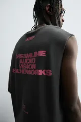 Sudadera sin mangas (tipo chaleco) de color gris oscuro con efecto lavado, corte relajado y cuello redondo. Presenta un estampado frontal en color rosa neón con texto y gráficos abstractos.