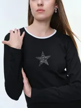 Remera de manga larga entallada, confeccionada en algodón elastizado. Presenta cuello redondo en color blanco a contraste y un detalle de estrella central compuesta por brillos.