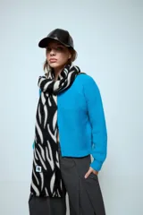 Bufanda rectangular con estampado animal print de cebra en blanco y negro, con detalle de etiqueta cuadrada con logo en el extremo inferior.