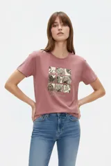 Remera color rosado con cuello redondo, manga corta y estampa frontal de diseño gráfico con conchas marinas.
