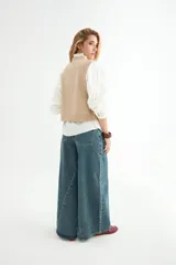 Chaleco tejido de punto color verde salvia, con cuello redondo y diseño sin mangas. Presenta detalles de pequeños apliques brillantes distribuidos por toda la prenda.