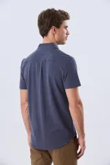 Camisa de piqué lisa color celeste, de manga corta, con cuello camisero y cierre frontal de botones oscuros.