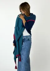 Chal de lana tejido con diseño de bloques de color gris, negro y crudo, con flecos borgoña en los extremos.