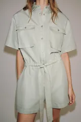 Mono corto de Zara Woman Collection color verde menta, confeccionado en mezcla de algodón y lino. Presenta cuello solapa, manga corta, cierre frontal con botones, bolsillos de plastrón con solapa en el pecho y cintura ajustable con lazo.