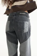 Jean de tiro medio con diseño de recortes en bloques de denim en tonos gris y negro, de corte recto.