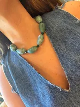 Collar tipo gargantilla con cuentas grandes de piedra o acrílico verde agua con vetas blancas, intercaladas con cuentas pequeñas de cristal facetado verde oscuro.