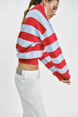 Sweater de punto con diseño de rayas horizontales en rojo y celeste, cuello polo blanco con escote en V y manga larga.