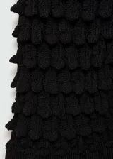 Buzo de punto fino color negro, con diseño entallado, cuello redondo y mangas cortas. Presenta un tejido con textura en relieve.
