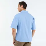 Camisa de manga corta de mezcla de lino en color celeste, con cuello cubano, cierre frontal con botones y un bolsillo aplicado en el pecho.
