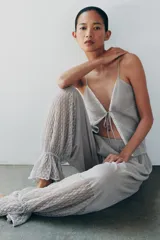 Pantalón abombacho semitransparente de tejido de encaje suave color gris, con tiro medio, cintura elástica y diseño con calados y volantes en los tobillos.