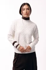 Sweater de tejido de punto con textura de pequeños relieves circulares, cuello redondo y mangas largas. Presenta un calce relajado con puños y ruedo acanalados.