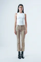 Jean de corte bootcut y tiro medio en color beige, con diseño de cinco bolsillos y cierre frontal con botón y cremallera.