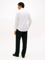 Camisa blanca de vestir Tommy Hilfiger, de corte slim fit, manga larga y cuello clásico. Confeccionada en algodón regenerativo, algodón BCI y elastano. Incluye logo bordado en el pecho.