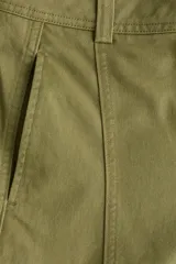 Pantalón de sarga de algodón verde militar, de tiro alto con piernas estilo barrel y costuras frontales destacadas. Cuenta con cierre de cremallera y botón oculto, bolsillos discretos en las costuras laterales y bolsillos traseros insertados.