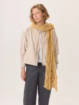Bufanda de lana tejida con diseño de trama abierta y textura irregular, en tonos amarillo mostaza y blanco.