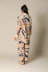 Pantalón de malla con estampado tie-dye en tonos rojo y azul oscuro. Presenta una silueta relajada y cintura ajustada.