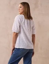 Blusa blanca de tejido calado, marca Sabrina Lauren. Cuello a la base y abertura central con botones.