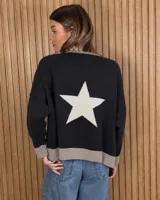 Buzo de punto negro con diseño oversize, cuello redondo, mangas largas y una gran estrella blanca en la espalda. Presenta ribetes en tono tostado en el cuello, los puños y el ruedo.