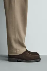 Bota estilo Chelsea con parte superior de piel con acabado en serraje, elásticos laterales para facilitar el calce, horma redonda y suela con ligero tacón.