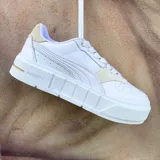 Championes urbanos Puma modelo Cali Court Match, color blanco con detalles en beige claro en el talón y la puntera. Presentan una suela de plataforma robusta y diseño minimalista con el logo de la marca en el lateral y la lengüeta.