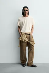 Camiseta relaxed fit color gris oscuro, confeccionada en tejido ligero de algodón con elasticidad. Presenta cuello redondo y manga ranglán corta.