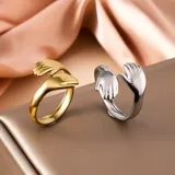 Set de dos anillos unisex, uno dorado y otro plateado, con diseño de manos abrazándose.