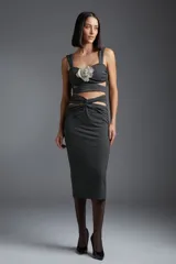 Top negro con estampado de lunares blancos, breteles anchos y detalle de flor blanca en el centro.