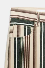 Jeans de tiro medio con diseño de rayas verticales en tonos beige, marrón y verde, corte boyfriend, cinco bolsillos y cierre frontal con cremallera y botón.