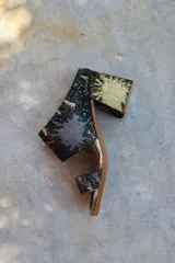 Sandalias de tacón alto con diseño de dos tiras anchas, confeccionadas en tela con estampado abstracto en tonos dorados y negros. Presentan un tacón cuadrado forrado en el mismo tejido.